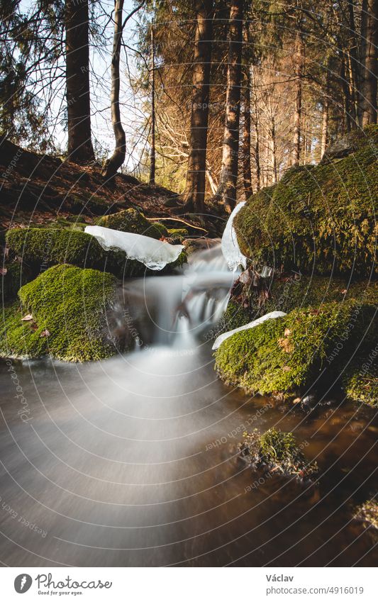 Klares Wasser, fotografiert mit langer Belichtungszeit, durch fließende, moosbewachsene Felsen mit herbstlichen Blattfarben. Beskiden, Tschechische Republik, Herz von Europa