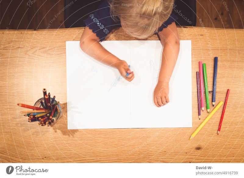 Kind mal an einem Tisch etwas auf ein großes Blatt Papier malen zeichnen kreativ zu Hause Kunst Buntstifte Stifte Hände lernen Kindergarten Spaß