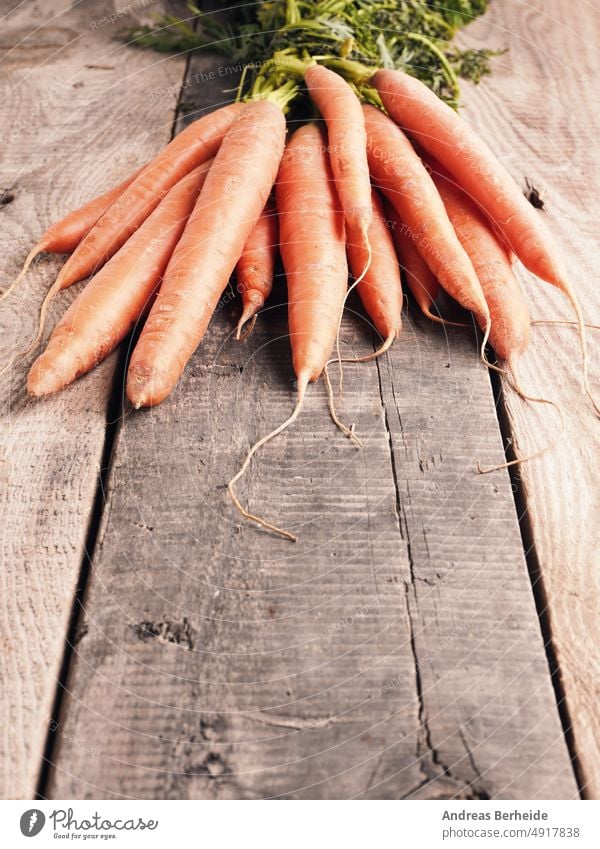 Leckere Bio-Möhren auf einem rustikalen Holztisch Karotten Veggie geschmackvoll saftig Karotin farbenfroh Biografie hölzern natürlich lecker produzieren