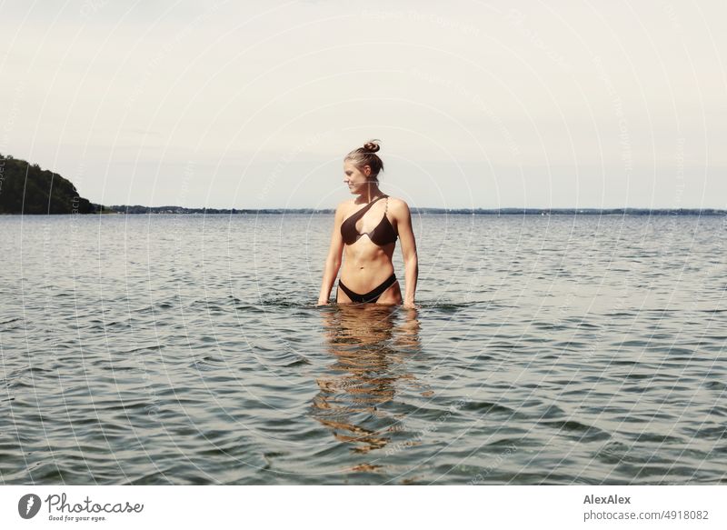 Junge, schöne, große  Frau in schwarzem Bikini im flachen Wasser in der Ostsee Lifestyle Gegenlicht gesund sportlich schlank ästhetisch jugendlich anmutig