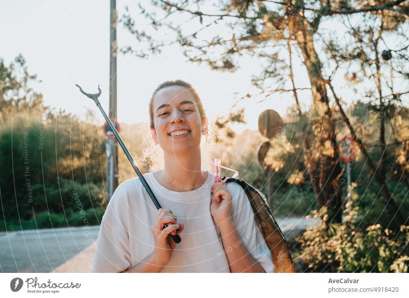 Volunteer Mädchen Reinigung des Waldes von Verschmutzung und Kunststoffen bei Sonnenuntergang mit Müll, lächelnd in die Kamera, glücklich umweltfreundlichen day.Nature Reinigung, Ökologie grünes Konzept.Environment Kopie Raum