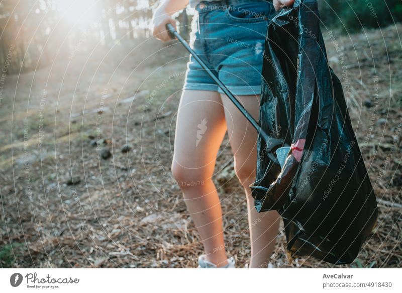 Junge Frau Freiwillige Reinigung des Waldes und sammeln Müll in eine Tasche. Nachhaltigkeit, den Planeten zu retten.Natur Reinigung, Ökologie grünes Konzept.Umwelt Kunststoffverschmutzung mit Kopie Raum