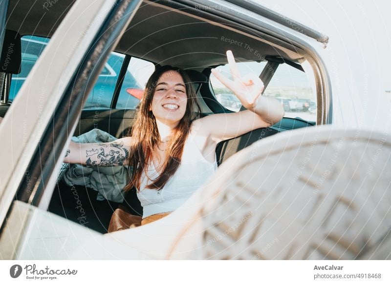 Super glückliche und positiv lächelnde junge Frau mit Tattoos, die sich nach einem Roadtrip-Tag in ihrem Auto ausruht. Sorglos Urlaub freie Zeit Konzept. Freiheit und Freiheit Konzept. Gen Z im Freien Spaß.