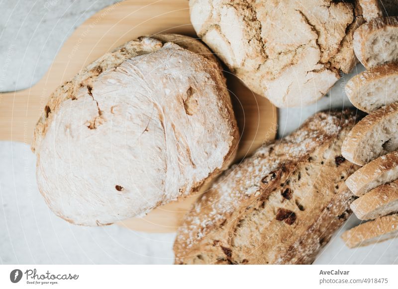 Verschiedene Arten von frisch gebackenem handwerklichem und biologischem Brot auf einem rustikalen Tisch. Hausgemachte Küche. Sauerteigbrot mit knuspriger Kruste auf Holzregal. Bäckerei Waren Konzept. Restaurant und Waren