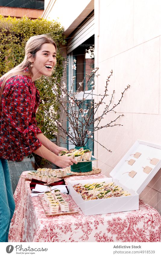 Zufriedene Frau serviert Tortilla-Rollen auf dem Tisch dienen rollen Snack Lebensmittel Amuse-Gueule Terrasse Festessen Speise geschmackvoll lecker appetitlich