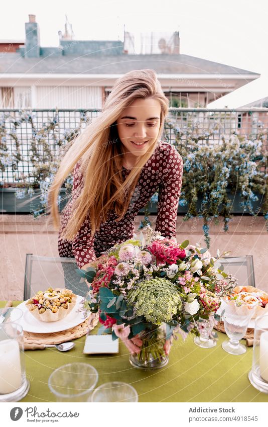 Frau arrangiert Tisch zusammen auf Terrasse einrichten Lebensmittel Blume Amuse-Gueule Festessen Zeit verbringen freie Zeit geschmackvoll Pflanze geblümt