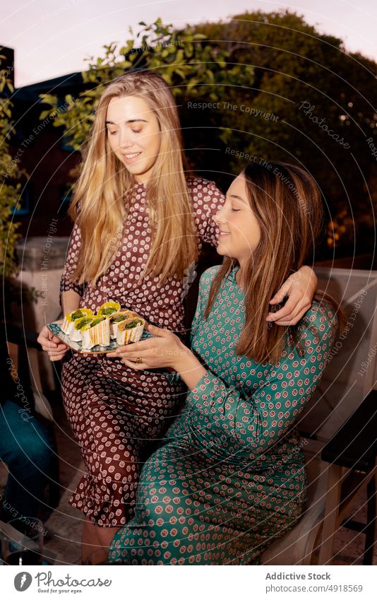 Frauen mit Tortilla-Rollen auf der Terrasse im Sommer Freund rollen Abendessen Zeit verbringen Snack Mahlzeit Anlass Freundschaft Lebensmittel Amuse-Gueule