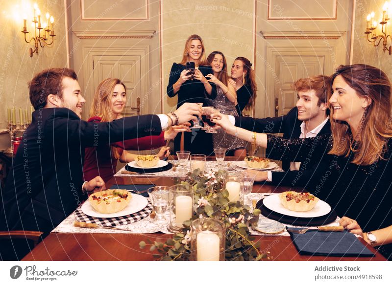 Freunde stoßen im Restaurant mit Weingläsern an jubelt Klirren Glas Menschengruppe Zuprosten Alkohol feiern Anlass Abendessen Wiedersehen Sitzung Mahlzeit