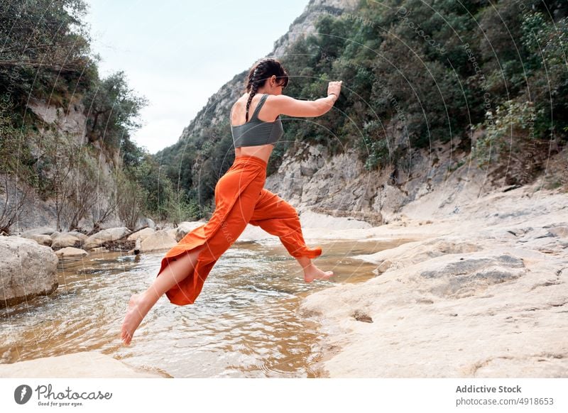 Junge Frau hat Spaß im Fluss Wald Urlaub Lifestyle Natur reisen jung springend Steine im Freien Menschen Freizeit Aktivität Abenteuer See Wanderung Feiertag