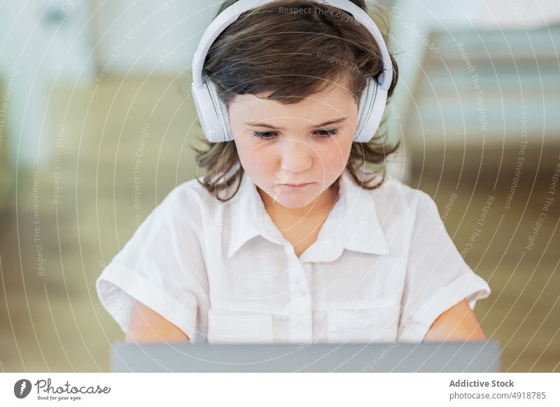Mädchen vor einem Laptop sitzend jung heimwärts Computer Schüler Bildung Kopfhörer Lernen Fokus schön Browsen studierend online Internet Person ernst