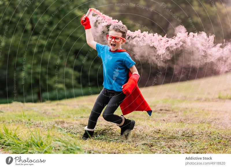 Kleiner Superheld mit Rauchbombe läuft herum Junge Park aufgeregt Tracht spielen Kraft Rasen laufen farbenfroh hell Lächeln Kind Glück Vorstellungskraft