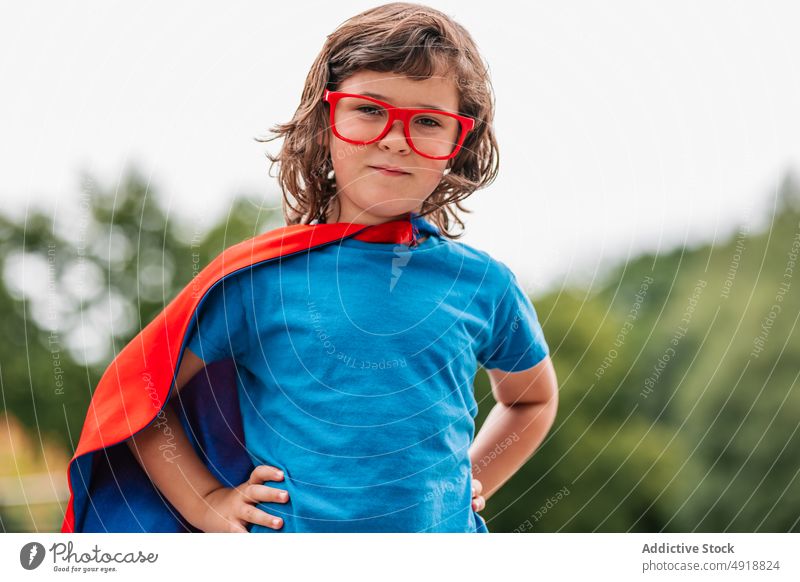 Kleiner Superheld mit fliegendem Umhang Mädchen Mut Sommer Park Fliege Kap so tun, als ob spielen Wochenende Tracht Himmel grau Kind selbstbewusst Kindheit