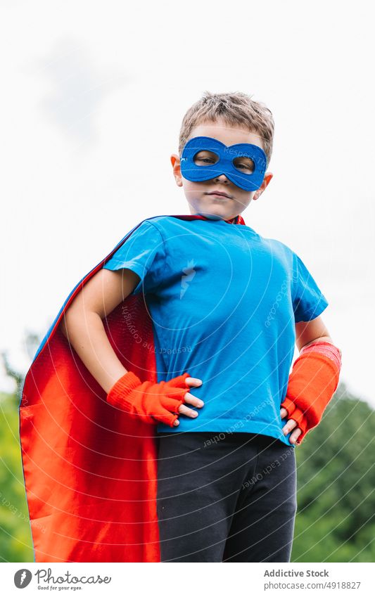 Kleiner Superheld mit fliegendem Umhang Junge Mut Sommer Park Fliege Kap so tun, als ob spielen Wochenende Tracht Himmel grau Kind selbstbewusst männlich
