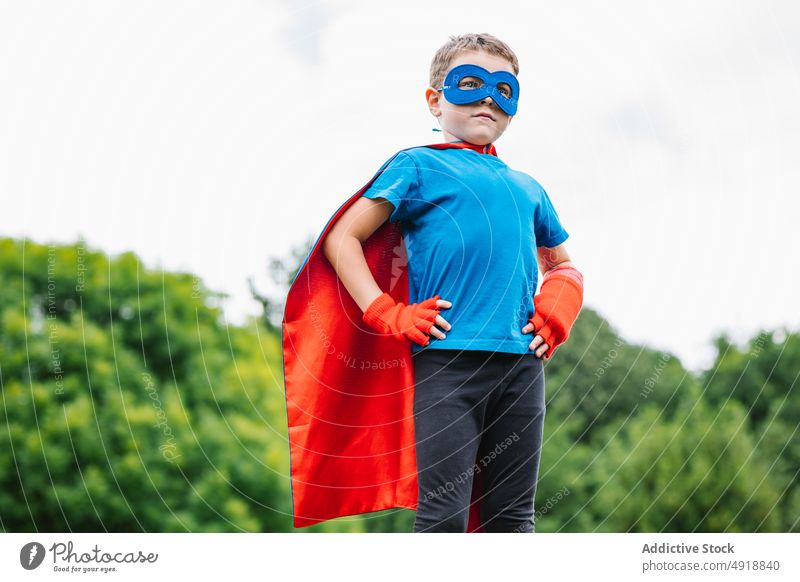 Kleiner Superheld mit fliegendem Umhang Junge Mut Sommer Park Fliege Kap so tun, als ob spielen Wochenende Tracht Himmel grau Kind selbstbewusst männlich