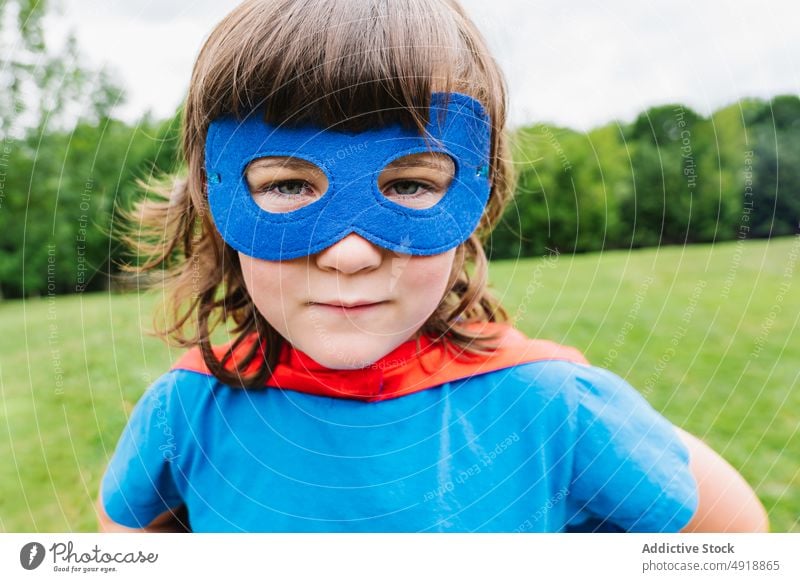 Kleines Mädchen mit Superheldenmaske Mundschutz Park spielen Wochenende Tracht ernst Sommer inkognito behüten Kind Vorstellungskraft furchtlos Mut stark