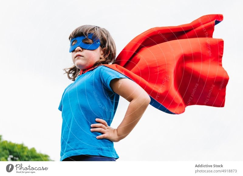 Kleiner Superheld mit fliegendem Umhang Mädchen Mut Sommer Park Fliege Kap so tun, als ob spielen Wochenende Tracht Himmel grau Kind selbstbewusst Kindheit