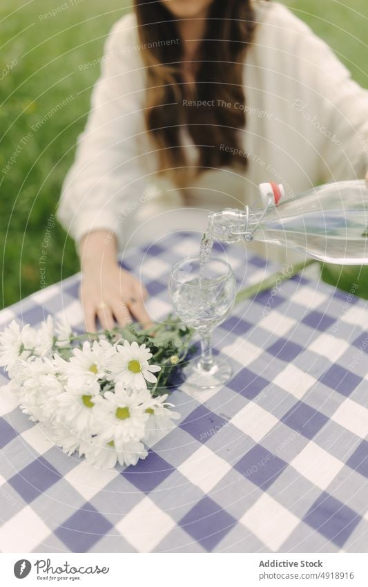 Unbekannte Frau gießt Wasser in einen Becher auf einem Feld eingießen Glas Tisch Kelch Erfrischung Getränk Landschaft Natur Zeitvertreib Erholung trinken