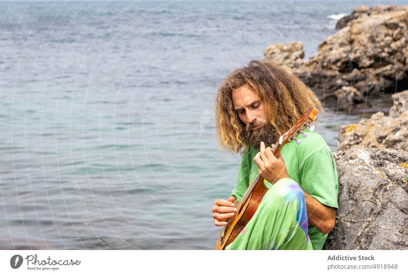 Talentierter männlicher Gitarrist spielt Ukulele auf einer felsigen Klippe Mann spielen Musiker Natur Instrument ausführen akustisch Gitarrenspieler jung