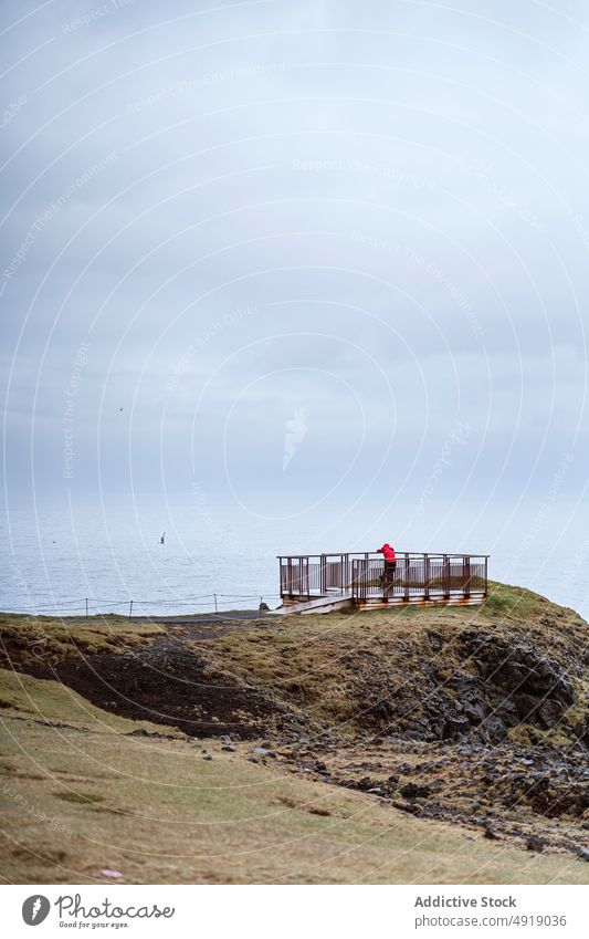 Reisende auf einem Aussichtspunkt am Meer Reisender bewundern MEER Ufer wolkig Himmel grau ruhen Zaun Island Oberbekleidung Wetter kalt Tourist Küste Terrasse