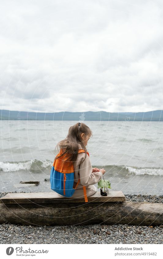 Anonymes kleines Mädchen spielt mit einem Blatt am Meeresufer See kalt Wasser Natur Winter Strand MEER Landschaft schön reisen im Freien blau Ansicht Tourismus