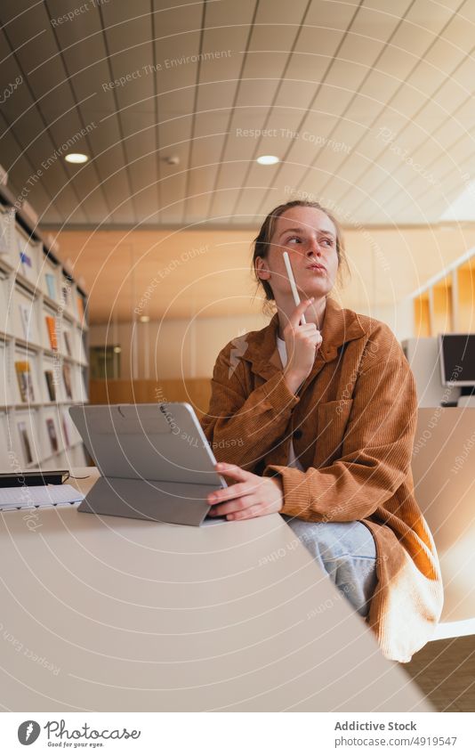 Junge Frau benutzt Tablet in einer Bibliothek Schüler Tablette benutzend Bildung Hausaufgabe lernen Universität Projekt jung Browsen Apparatur Hochschule Gerät