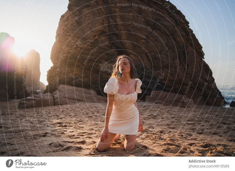 Frau sitzend am Strand mit Felsen Reisender MEER Wasser Ufer Sonnenuntergang Zeitvertreib sensibel Fernweh Stein feminin Kleid genießen Anmut Ausflug ruhen