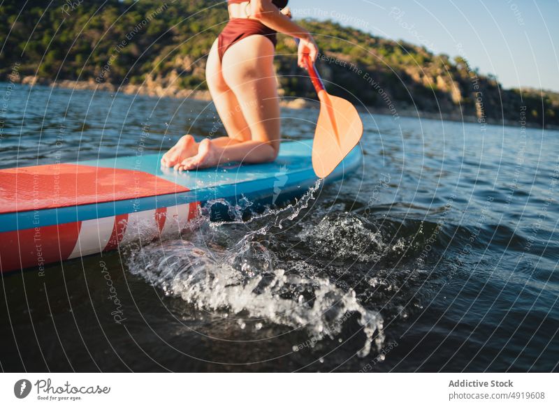 Frau schwimmt auf Paddelbrett im See sportlich Surfer Freizeit Hobby Wasser Reihe Schwimmer Küste Abenteuer Zusatzplatine Ufer Natur Gerät ruhen Felsen