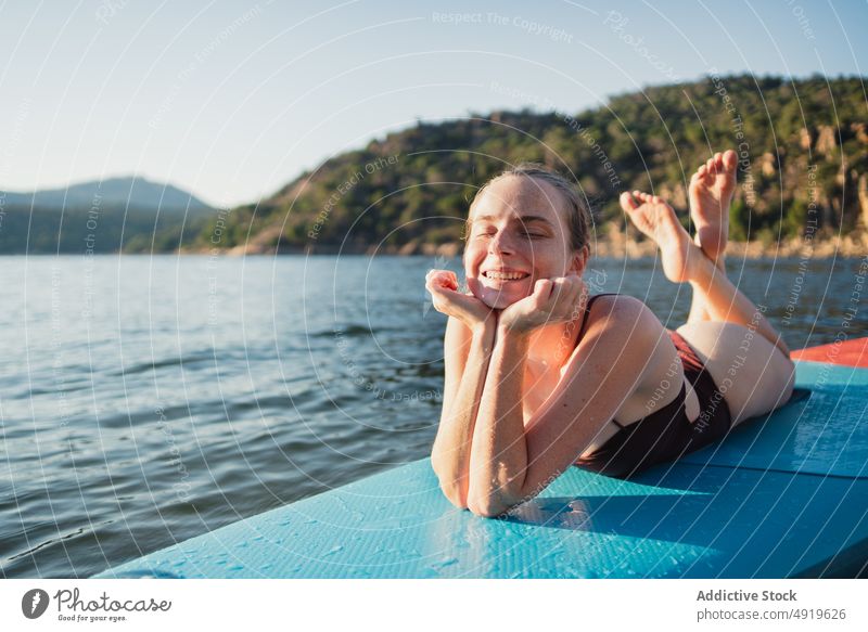 Frau auf Paddleboard im See liegend Paddelbrett Freizeit Hobby Wasser ruhen Natur Wohlbefinden Badebekleidung Sommer Zusatzplatine schlanke Ufer Schwimmer