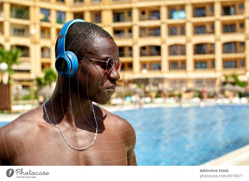 Schwarzer Mann hört Musik in der Nähe des Schwimmbads ruhen Erholung zuhören Gesang Hobby Schwimmsport Pool Zeitvertreib Klang Kopfhörer männlich maskulin Audio