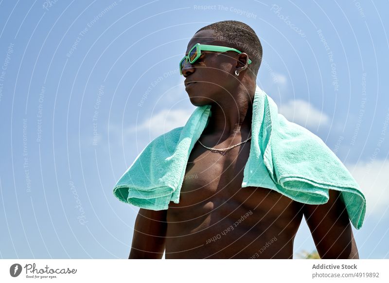 Schwarzer Mann ohne Hemd mit Handtuch nackter Torso ruhen Erholung Zeitvertreib tropisch Natur Sonnenbrille Vorschein Freizeit schwarz Afroamerikaner ethnisch