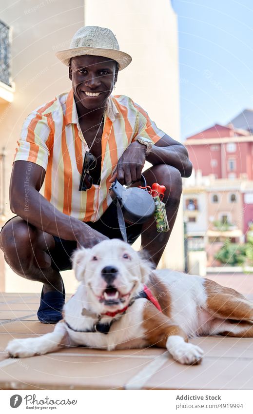 Freudiger schwarzer Mann mit Hund auf der Straße Haustier amerikanischer Pitbull-Terrier Großstadt Tier Besitzer Zeitvertreib Freizeit Freund zufrieden positiv