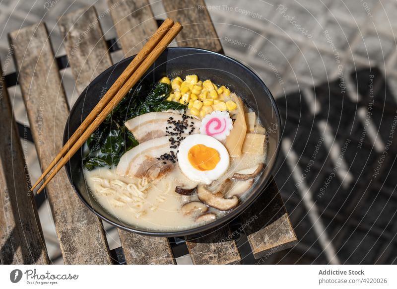 Leckere Ramen auf dem Bürgersteig serviert Japanisch Nudel traditionell Pilz Ei Kultur Speise Straßenbelag Straßenessen Bestandteil Brühe Laufsteg Sonnenlicht