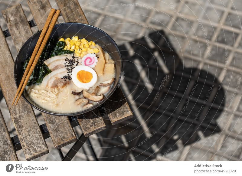 Leckere Ramen auf dem Bürgersteig serviert Japanisch Nudel traditionell Pilz Ei Kultur Speise Straßenbelag Straßenessen Bestandteil Brühe Laufsteg Sonnenlicht