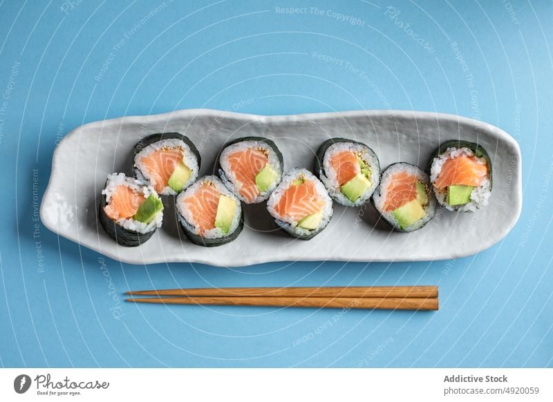 Leckere Futomaki-Norwegerollen mit Lachs Japanisch Sushi futomaki Kulisse Avocado Meeresfrüchte Fisch traditionell Essstäbchen Kultur Speise Lebensmittel Reis