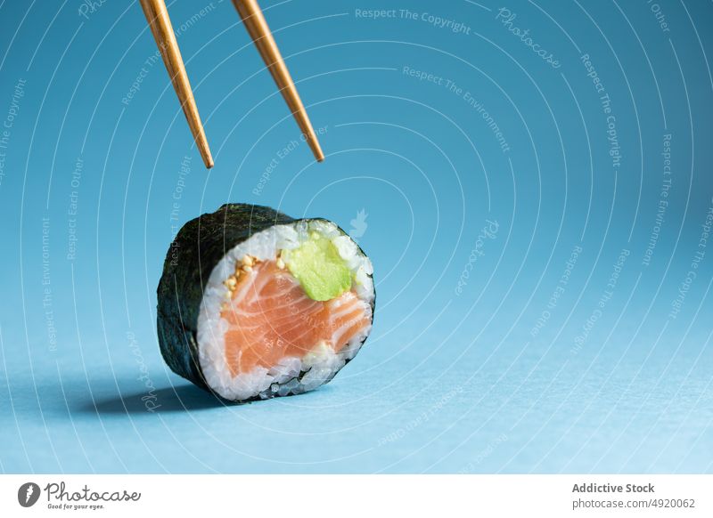 Futomaki-Sushi-Rolle mit Stäbchen Japanisch futomaki Asiatische Küche Norweger Lachs Avocado Fisch rollen Essstäbchen Utensil traditionell Meeresfrüchte