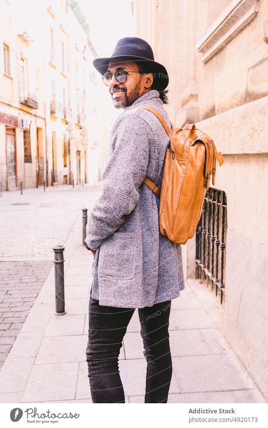 Positives trendiges Männchen auf der Straße in der Stadt Mann Spaziergang Bürgersteig Streetstyle Lächeln positiv urban Hand-in-Tasche tagsüber männlich Stil