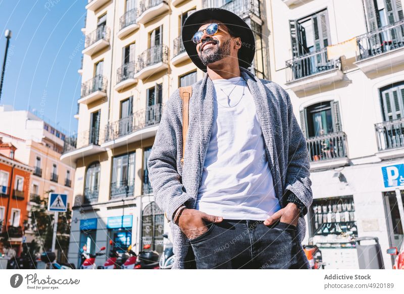 Stilvoller hispanischer Mann auf einer Straße in der Stadt Streetstyle urban tagsüber Outfit ruhen Vorschein männlich ethnisch Erwachsener Hand-in-Tasche modern