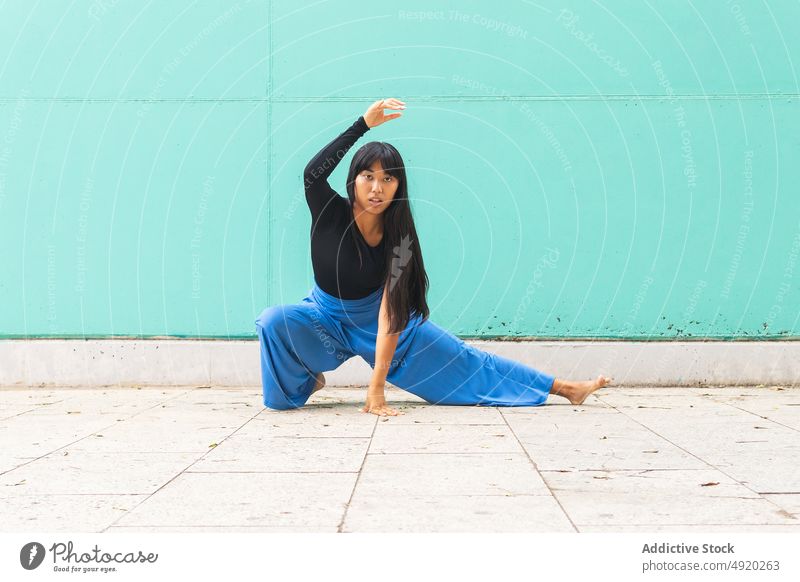 Asiatische Frau tanzt auf dem Bürgersteig Tanzen Straße Straßenbelag Anmut Wand Arm angehoben berühren Ausfallschritt urban jung asiatisch ethnisch Energie