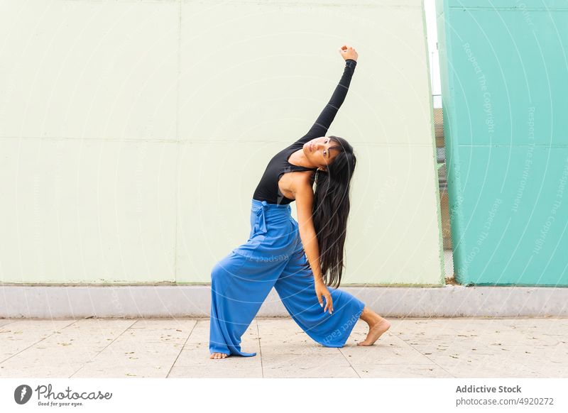 Asiatische Frau tanzt auf dem Bürgersteig Tanzen Straße Straßenbelag Anmut Wand Arm angehoben Ausfallschritt urban jung asiatisch ethnisch Energie Talent Barfuß