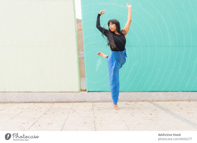 Asiatische Frau tanzt auf dem Bürgersteig Tanzen Straße Straßenbelag Anmut Wand Arm angehoben urban jung asiatisch ethnisch Energie Talent Barfuß lange Haare