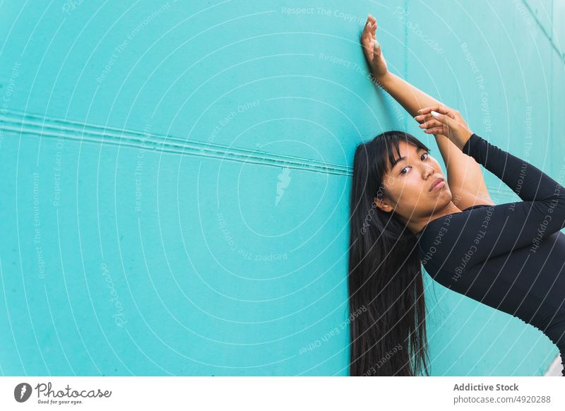 Flexible ethnische Frau im Trikot, die sich in der Nähe der Wand streckt Backend Dehnung berühren Anmut beweglich Sommer Tanzen Straße jung asiatisch Kunst