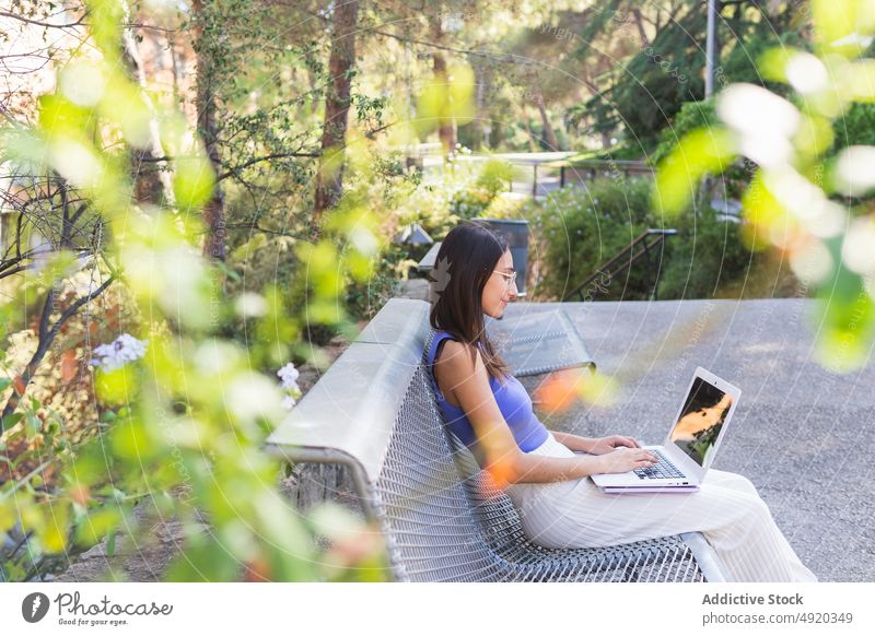 Glückliche Frau benutzt Laptop im Park Schüler Kommunizieren Gespräch online Großstadt Freude positiv reden Lächeln Netbook Gruß Rucksack benutzend Straße