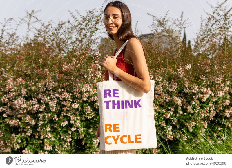 Zufriedene Frau mit Stoffbeutel auf der Straße Tasche umdenken recyceln Aufschrift umweltfreundlich keine Verschwendung Textil wiederverwerten sparen