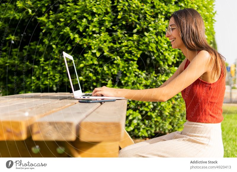 Studentin surft mit Laptop im Park Frau Schüler Hausaufgabe lernen Bildung Browsen online Projekt Baum Wissen klug Gerät Tippen vorbereiten sorgsam Suche