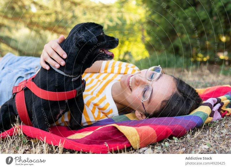 Glückliche junge Frau mit Hund auf bunter Decke Umarmung Park Wochenende Lächeln Besitzer Welpe Liebe Haustier froh Begleiter positiv Optimist bezaubernd ruhen