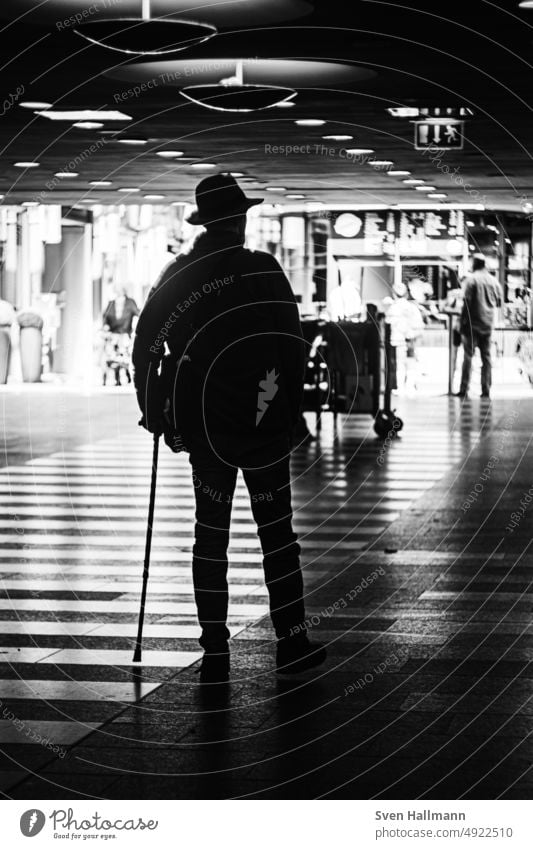 Mann geht am Stock durch Bahnhof schwarz-weiß Abstieg Schritt dunkel taumeln Beine Altstadt Metall Gitterrost Metallgeländer diagonal hell und dunkel