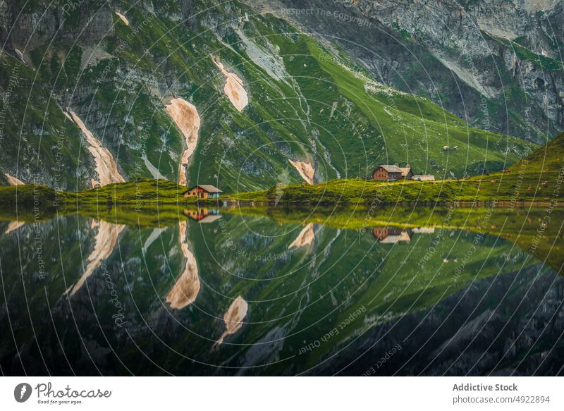 Malerische Landschaft mit ruhigem See, in dem sich Berge und Häuser spiegeln Berge u. Gebirge Natur Dorf Cottage Tal malerisch Hochland Wohnsiedlung