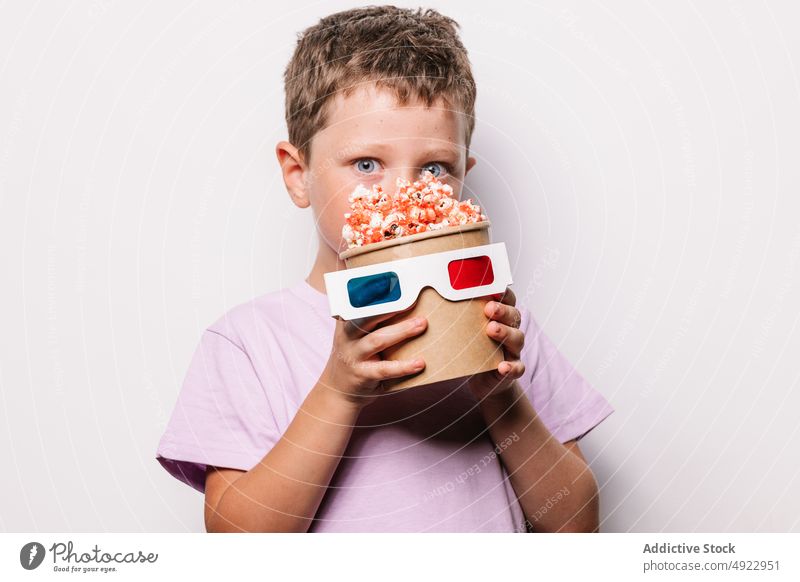 Fröhlicher Junge mit 3D-Brille und Popcorn Kind 3d Vergnügen Popkorn Snack Film Hobby Leckerbissen Glück Lebensmittel unterhalten Tierhaut Inhalt froh Optimist