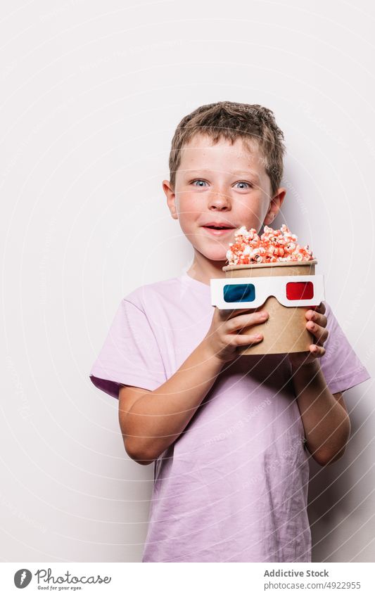Fröhlicher Junge mit 3D-Brille und Popcorn Kind 3d Vergnügen Popkorn Snack Film Glück Hobby Leckerbissen Lebensmittel unterhalten Inhalt froh Optimist lecker