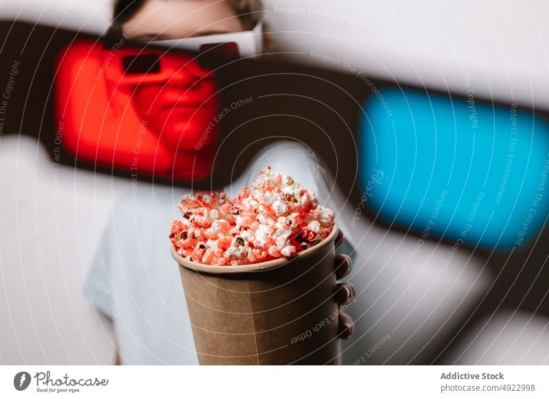 Durch rote Linse Blick auf Mädchen mit Popcorn Kind 3d Brille Vergnügen Popkorn Snack unterhalten Leckerbissen Hobby froh Optimist positiv Kino Lebensmittel